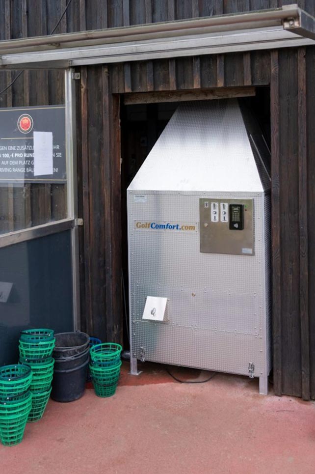 Ein UV-Schutzgerät steht vor einer dunklen Holzfassade, mit einem gebrauchten Golfplatz-Reinigungssystem, das an der Vorderseite einen Anzeigeschalter hat.